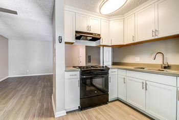 a kitchen with white cabinets and an oven and a sink  at Veranda La Mesa, California, 91942